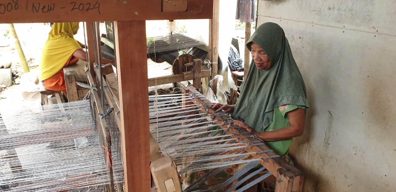Seorang pengrajin perempuan sedang menenun mendong di sebuah alat tenun tradisional di Tasikmalaya, menunjukkan keterampilan dan dedikasi dalam melestarikan budaya lokal.